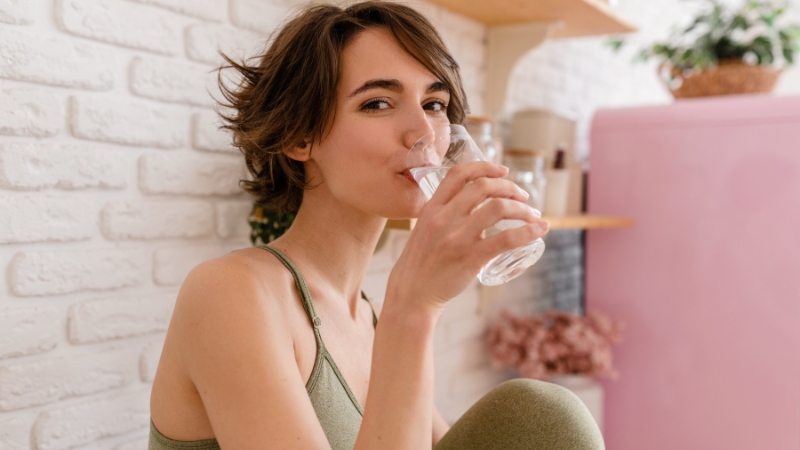 Žena pije čašu vode kod kuće