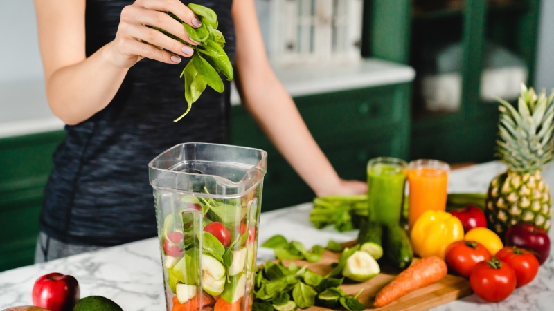 Žena sprema zdravi napitak od povrća i voća u kuhinji