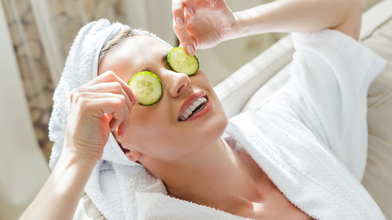 Žena sa peškirom na glavi drži kolutove krastavca na očima