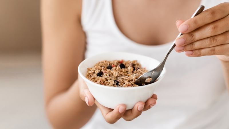 Žena drži činiju sa ovsenim pahuljicama i suvim voćem kao proteinski doručak za mršavljenje